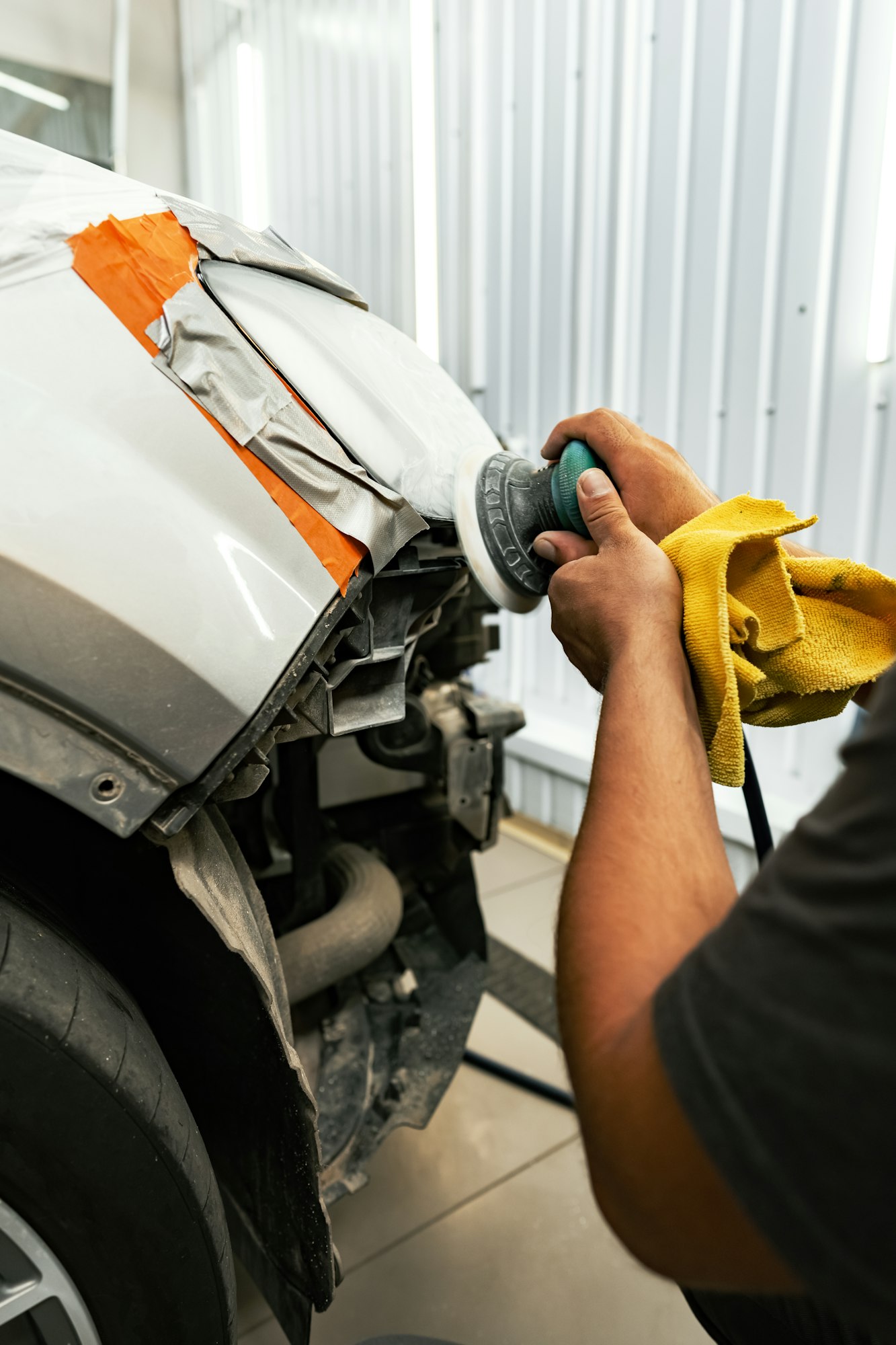 Close up of car cleaner polishing headlight with polish machine