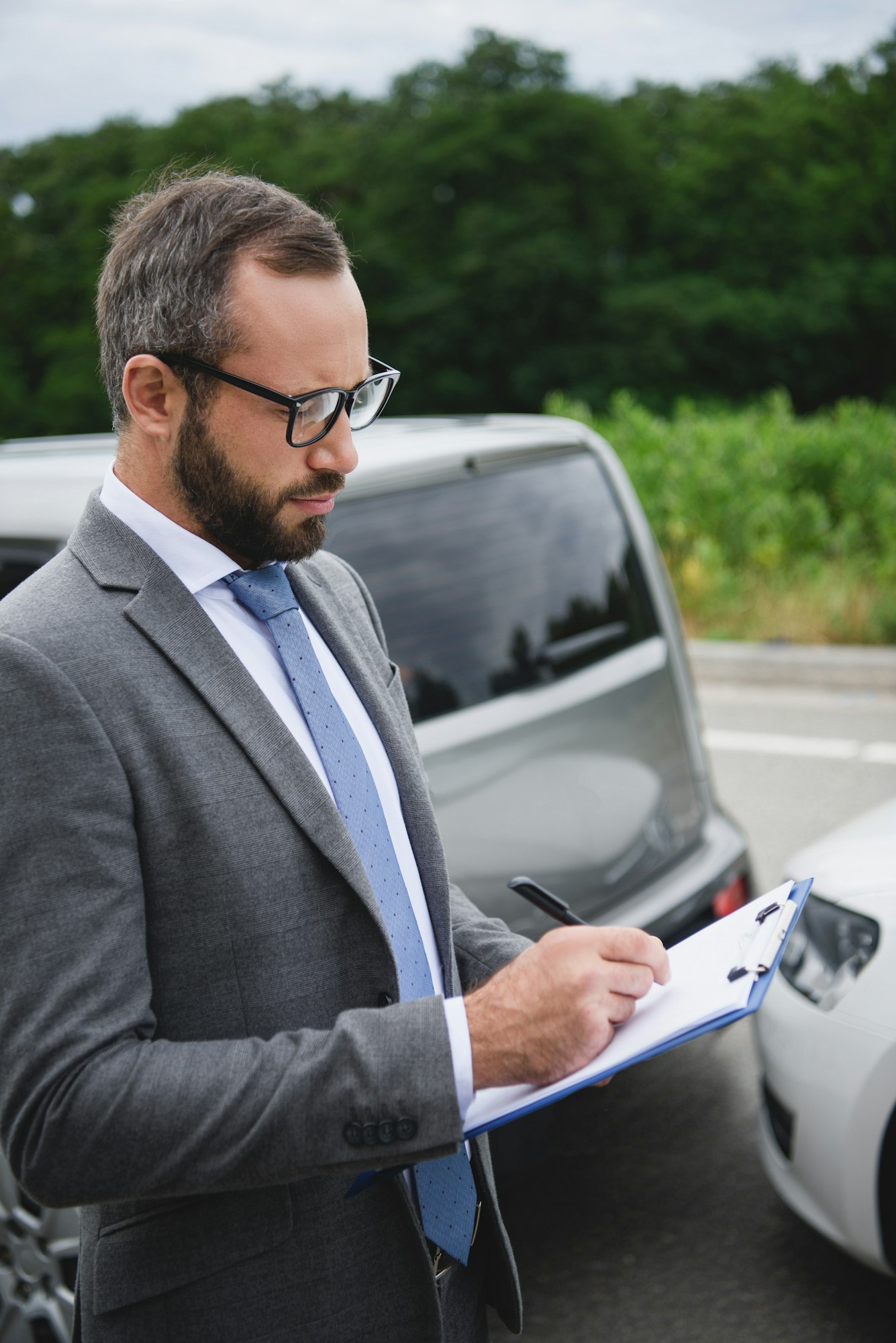 handsome man writing something to car insurance after car accident