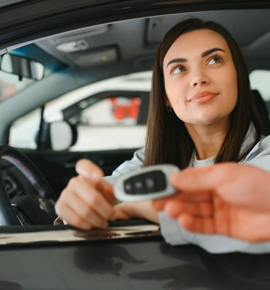 Car dealer giving key to new car owner